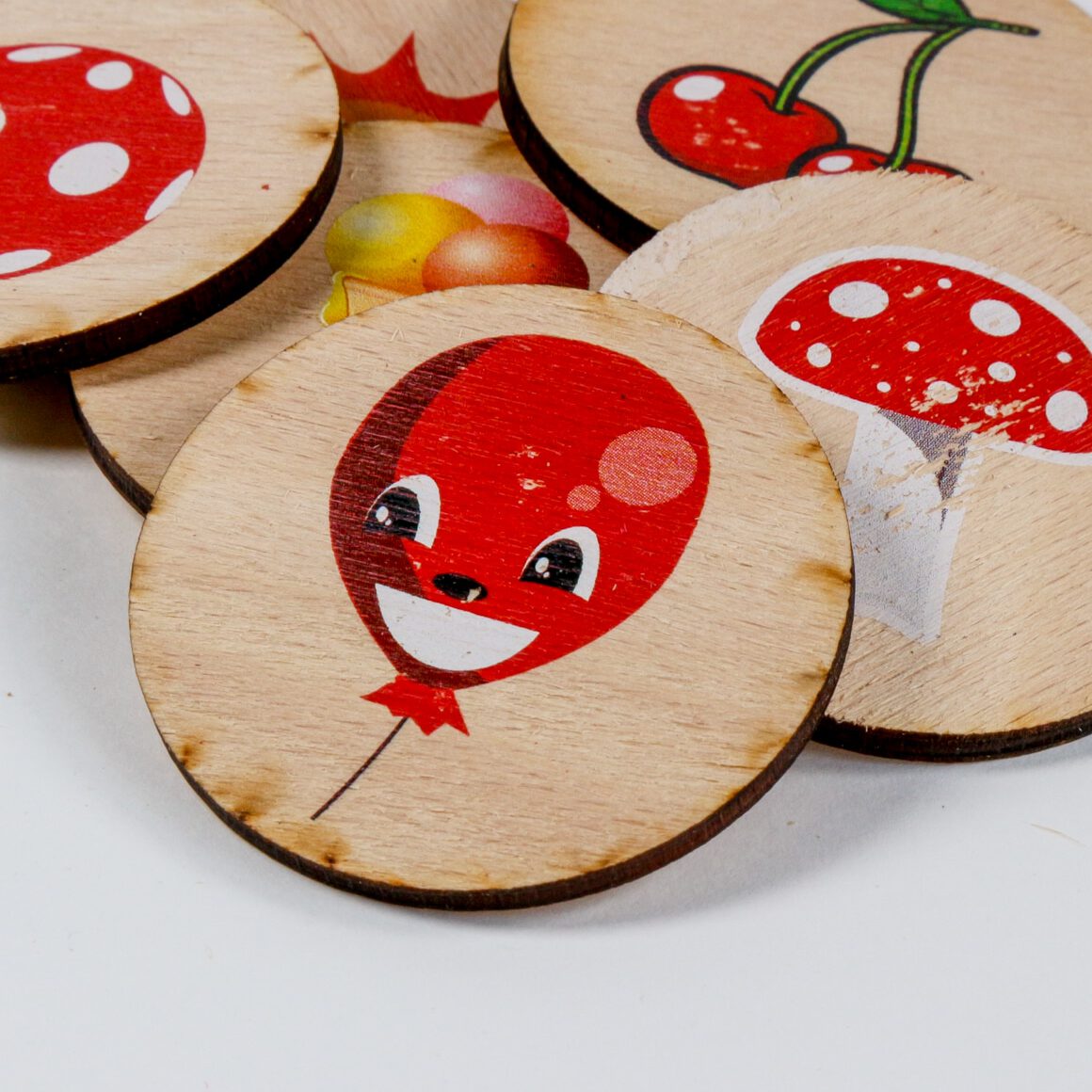 Színes ovis jelek fa táblácskákon. Látható egy lufi, gomba, cseresznye, fagyi és labda.