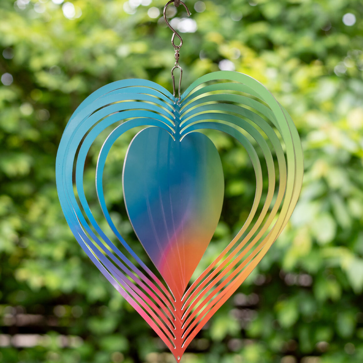 Háttérben homályos fák láthatóak. Egy szív alakú fém szélforgó látható, mely szivárvány színekben pompázik. Közepén egy nagyobb szív felület található, erre akár fotó is kerülhet.