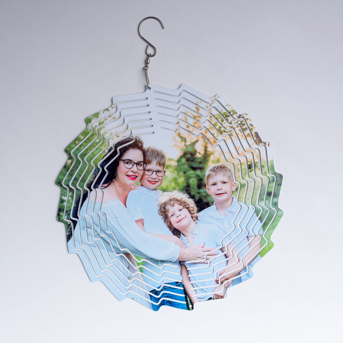 Egy fém szélforgó látható, melyre egy kép lett nyomtatva egy anyáról és gyermekeiről.